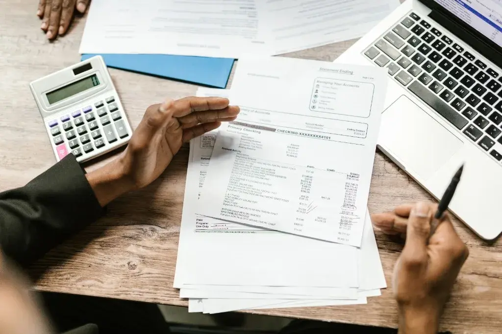 Financial expert reviewing bank statements and account activity with calculator and laptop